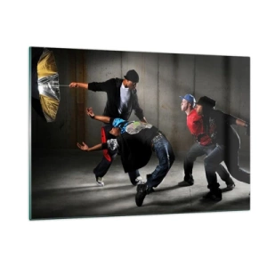 Obraz na szkle - Grupa tancerzy w dynamicznej pozie na tle industrialnym - 120x80cm - Tańczący z ulicznym wiatrem - Nowoczesna dekoracja ścienna do salonu, kuchni i sypialni ARTTOR