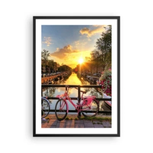 Plakat w czarnej ramie - Różowy rower na moście nad kanałem przy zachodzie słońca - 50x70cm - Wiosenny poranek w Amsterdamie - Nowoczesna dekoracja ścienna do salonu i sypialni ARTTOR