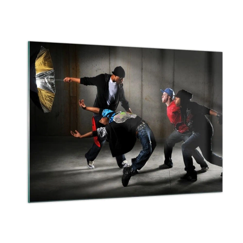 Obraz na szkle - Grupa tancerzy w dynamicznej pozie na tle industrialnym - 100x70cm - Tańczący z ulicznym wiatrem - Nowoczesna dekoracja ścienna do salonu, kuchni i sypialni ARTTOR