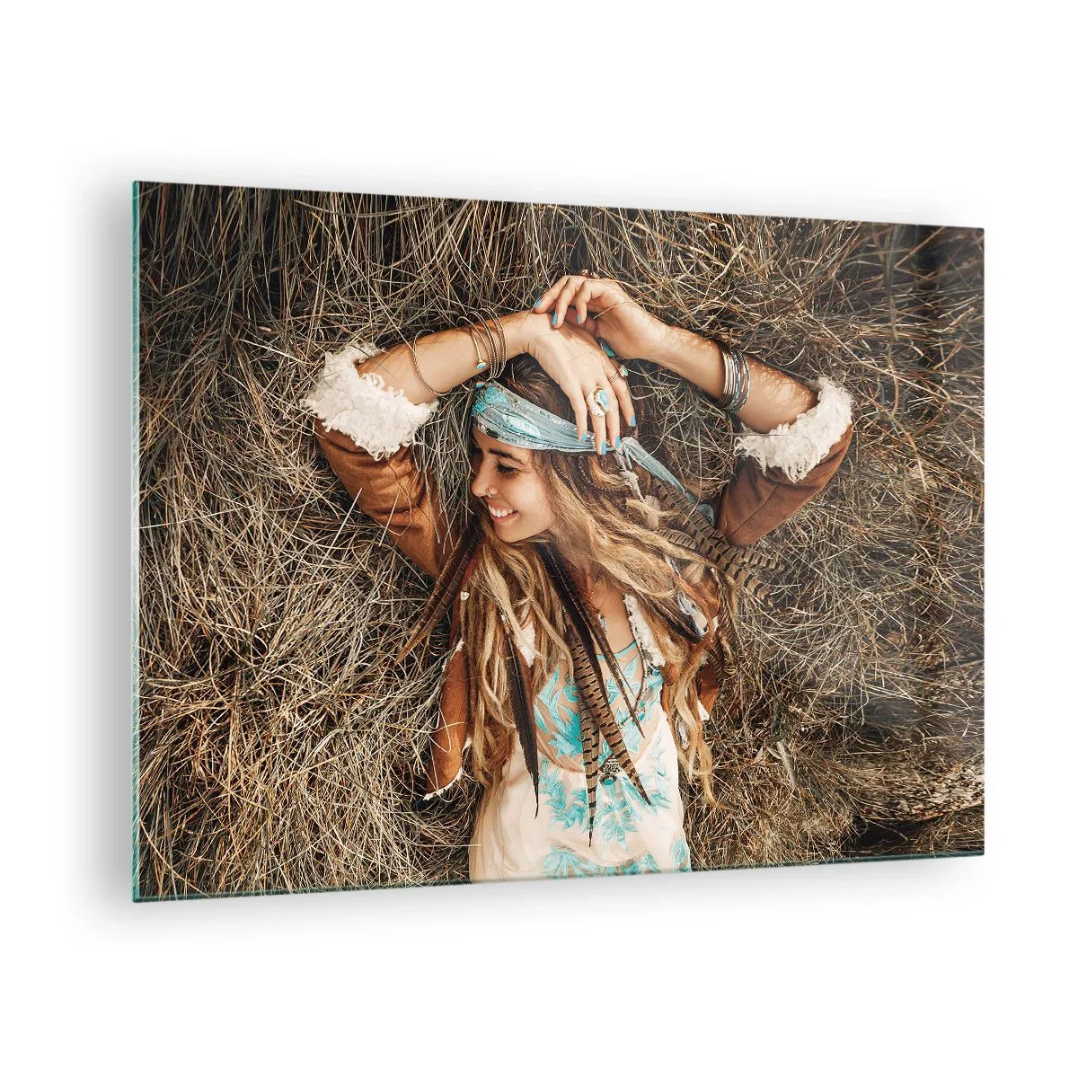 Obraz na szkle - Kobieta w stylu boho leżąca w sianie z uśmiechem - 70x50cm - W drodze do lata miłości - Nowoczesna dekoracja ścienna do salonu i sypialni ARTTOR
