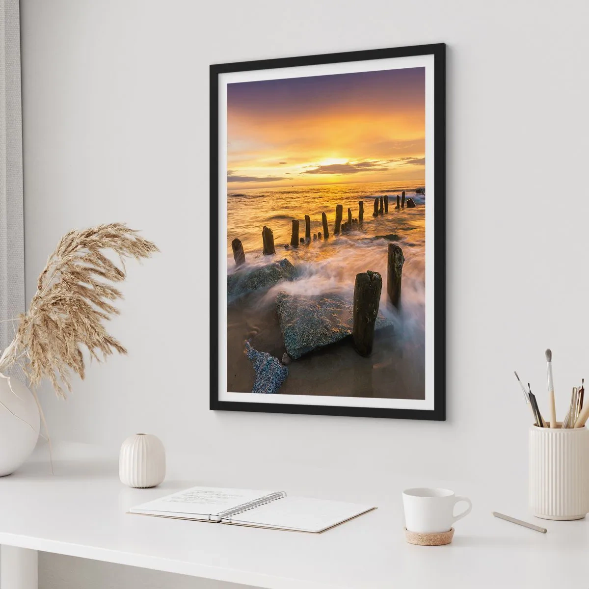 Plakat w czarnej ramie - Zachód słońca nad morzem z drewnianymi paliami na plaży - 50x70cm - Surowe piękno Bałtyku - Nowoczesna dekoracja ścienna do salonu i sypialni ARTTOR