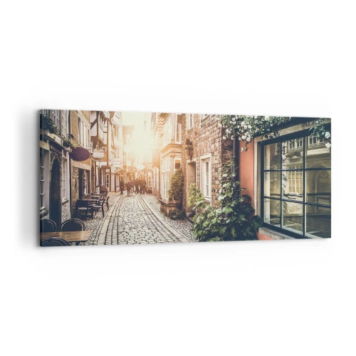 Obraz na płótnie - Urokliwa uliczka z kamiennym brukiem i kwiatami - 120x50cm - Różany zaułek w różowym blasku - Nowoczesna dekoracja ścienna do salonu i sypialni ARTTOR