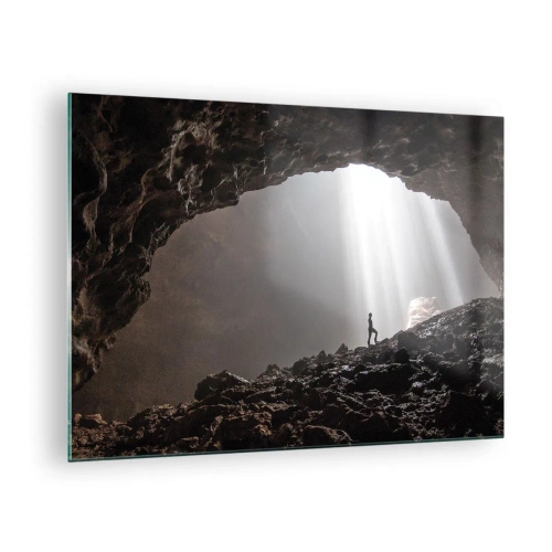 Obraz na szkle - Postać w jaskini oświetlonej promieniami światła, otoczonej przez ciemne skały - 70x50cm - Świetlista grota - Nowoczesna dekoracja ścienna do salonu i sypialni ARTTOR