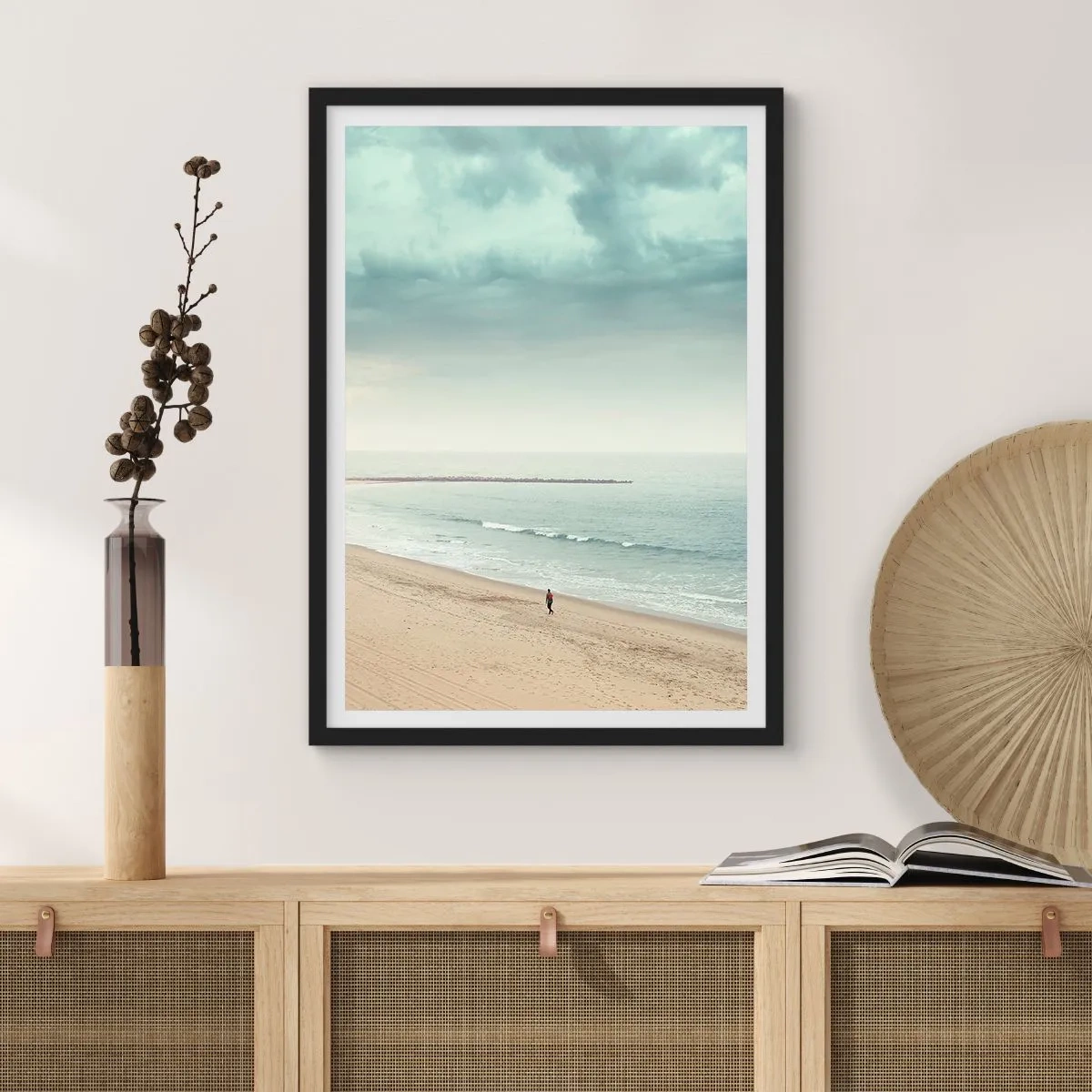 Plakat w czarnej ramie - Samotna postać spacerująca brzegiem morza pod zachmurzonym niebem - 50x70cm - w poszukiwaniu spokoju - Nowoczesna dekoracja ścienna do salonu i sypialni ARTTOR