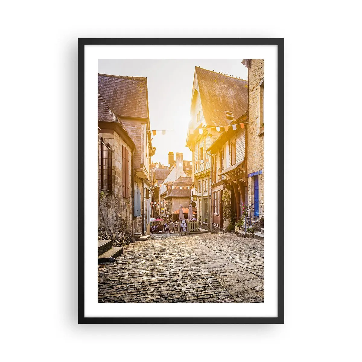 Plakat w czarnej ramie - Urokliwa uliczka z kamienicami w promieniach zachodzącego słońca - 50x70cm - Biały duch miasteczka - Nowoczesna dekoracja ścienna do salonu i sypialni ARTTOR