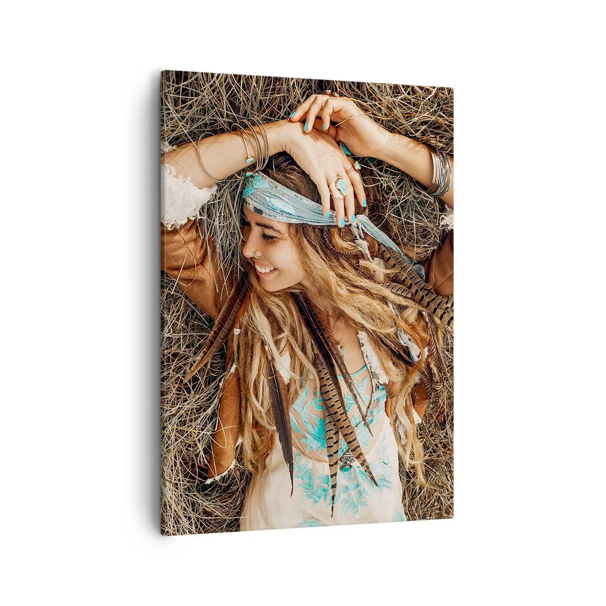 Obraz na płótnie - Kobieta w stylu boho z dredami i piórami leżąca na sianie - 50x70cm - W drodze do lata miłości - Nowoczesna dekoracja ścienna do salonu, kuchni i sypialni ARTTOR