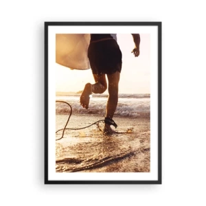 Plakat w czarnej ramie - Na spotkanie fali - Surfer wbiegający do wody o zachodzie słońca - 50x70cm