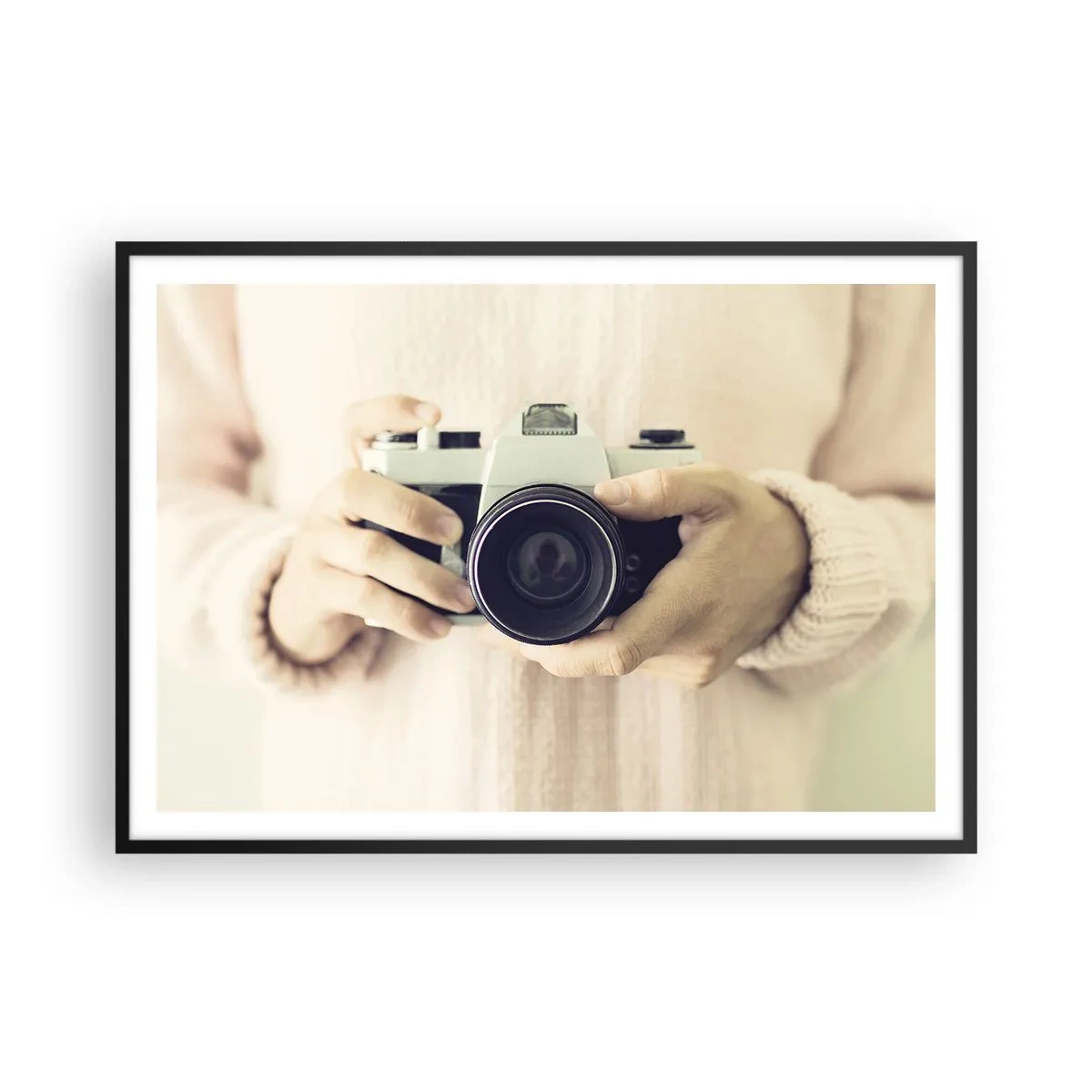 Plakat w czarnej ramie - Retro aparat fotograficzny trzymany w dłoniach na jasnym tle - 100x70cm - By widzieć więcej… - Nowoczesna dekoracja ścienna do salonu i sypialni ARTTOR