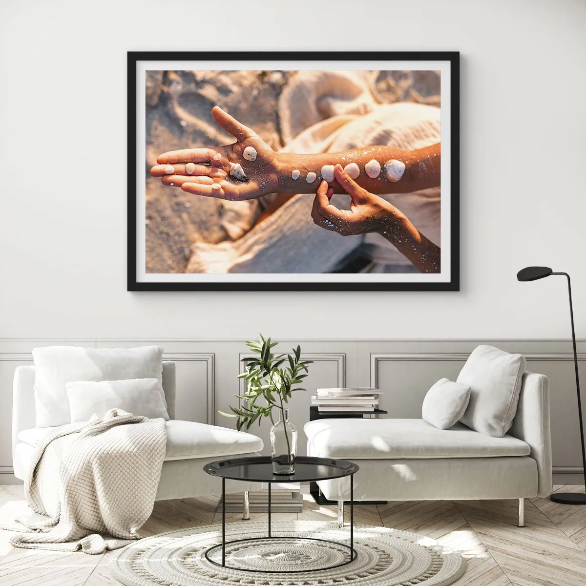 Plakat w czarnej ramie - Dłonie z ułożonymi muszlami na tle piasku - 70x50cm - Piękno w zasięgu ręki - Nowoczesna dekoracja ścienna do salonu i sypialni ARTTOR