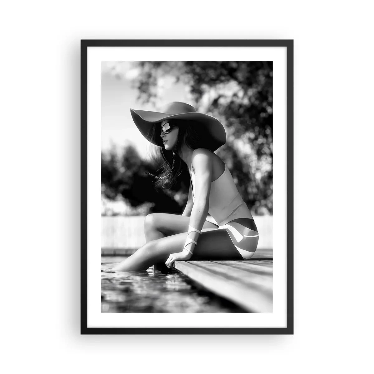 Plakat w czarnej ramie - Czarno-biała fotografia kobiety w kapeluszu siedzącej nad wodą - 50x70cm - Letnie marzenie - Nowoczesna dekoracja ścienna do salonu i sypialni ARTTOR