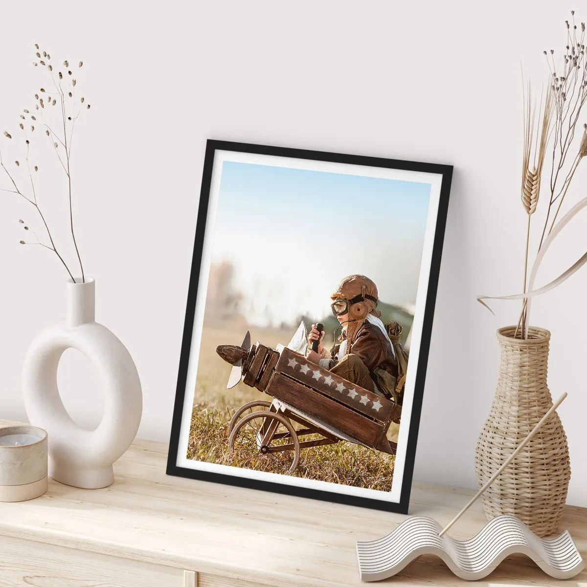 Plakat w czarnej ramie - Dziecko w drewnianym samolocie z gwiazdami na tle pola - 50x70cm - Start ku marzeniu - Nowoczesna dekoracja ścienna do salonu i sypialni ARTTOR