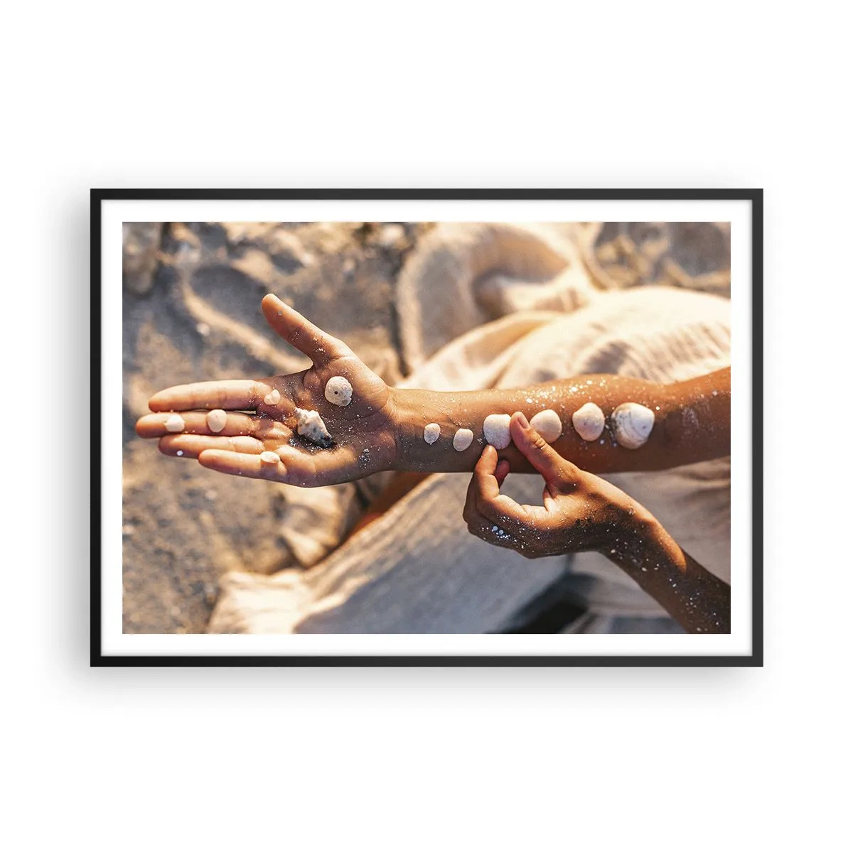Plakat w czarnej ramie - Dłonie z ułożonymi muszlami na tle piasku - 100x70cm - Piękno w zasięgu ręki - Nowoczesna dekoracja ścienna do salonu i sypialni ARTTOR