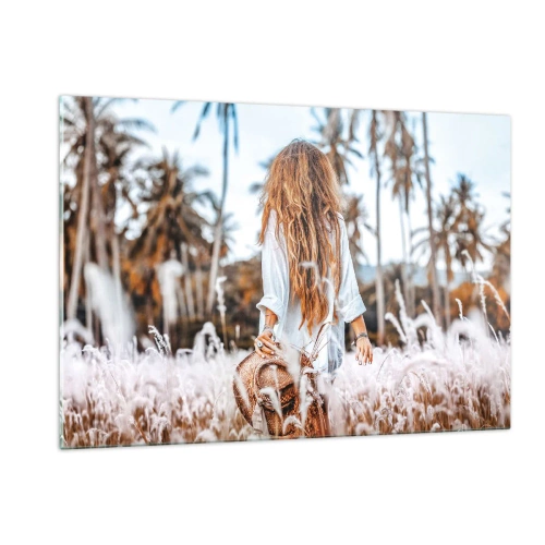 Obraz na szkle - Kobieta wśród traw z kapeluszem w ręku na tle palm - 120x80cm - Zrodzona z puchu traw - Nowoczesna dekoracja ścienna do salonu, kuchni i sypialni ARTTOR